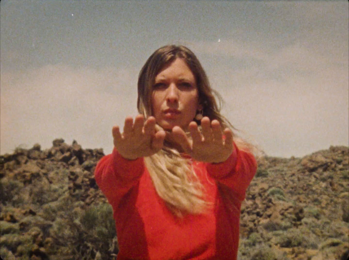 a woman in a red shirt is holding her hands up