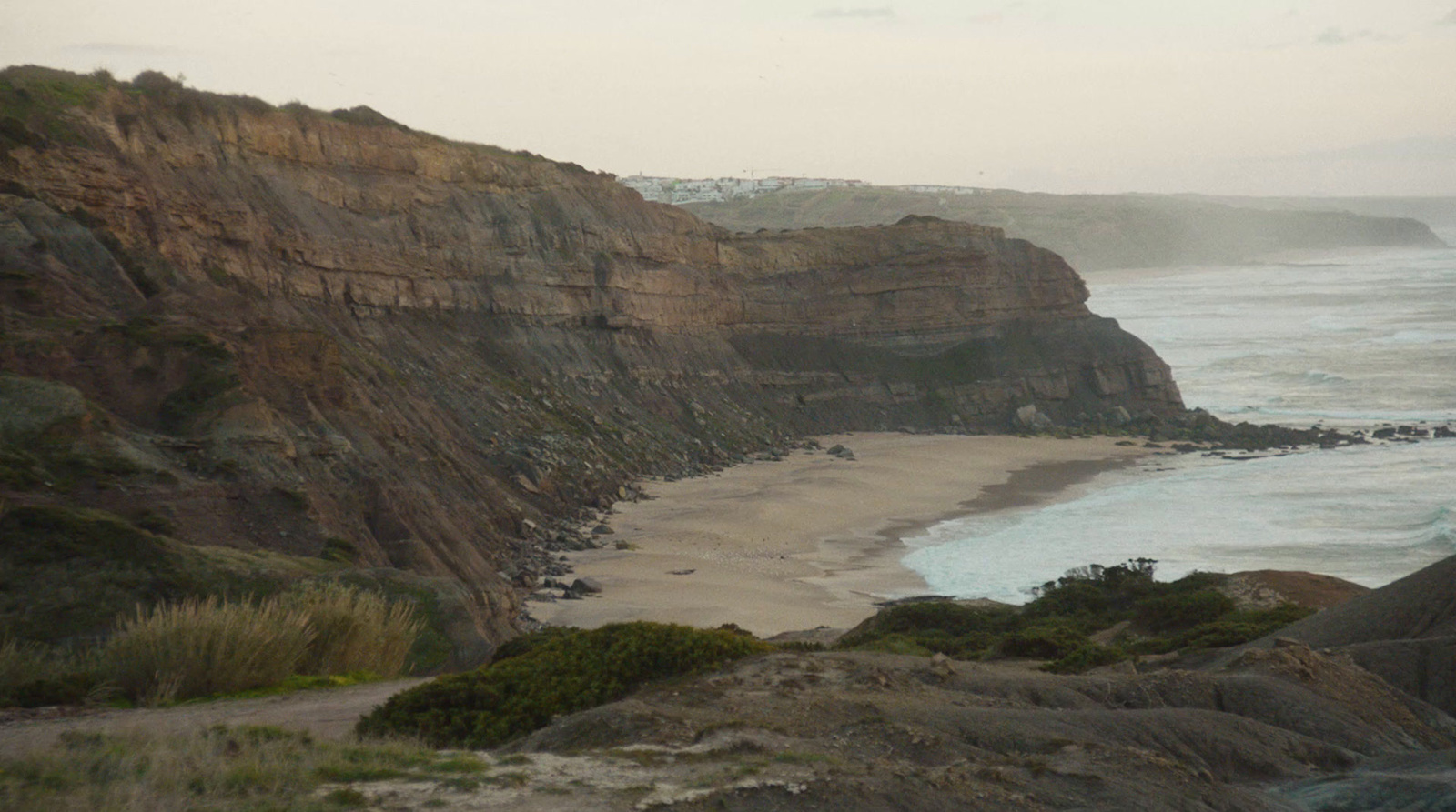 a view of a beach with a cliff in the background