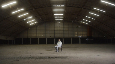 a woman in a white jacket standing in an empty building