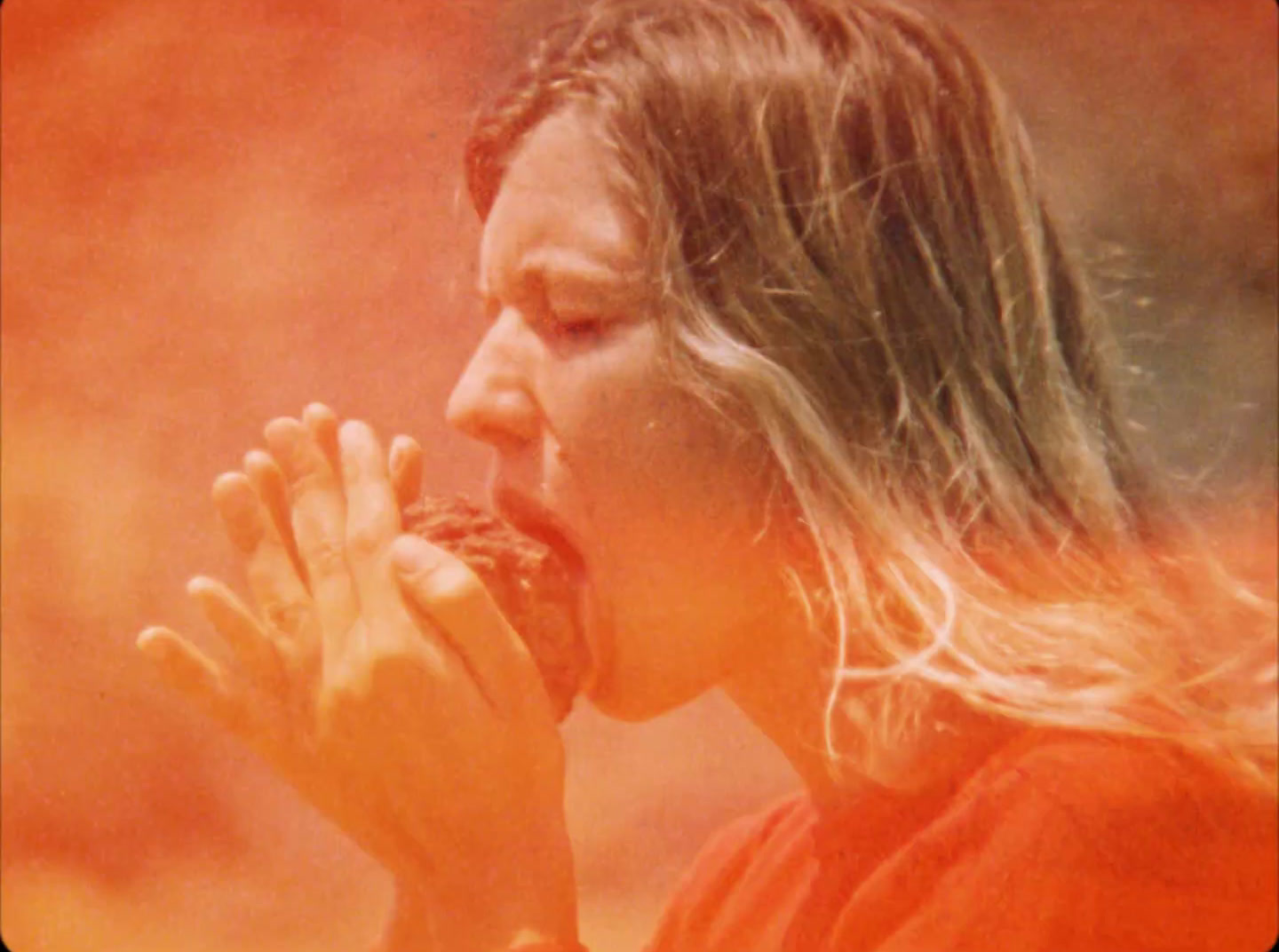 a woman with long hair eating a doughnut