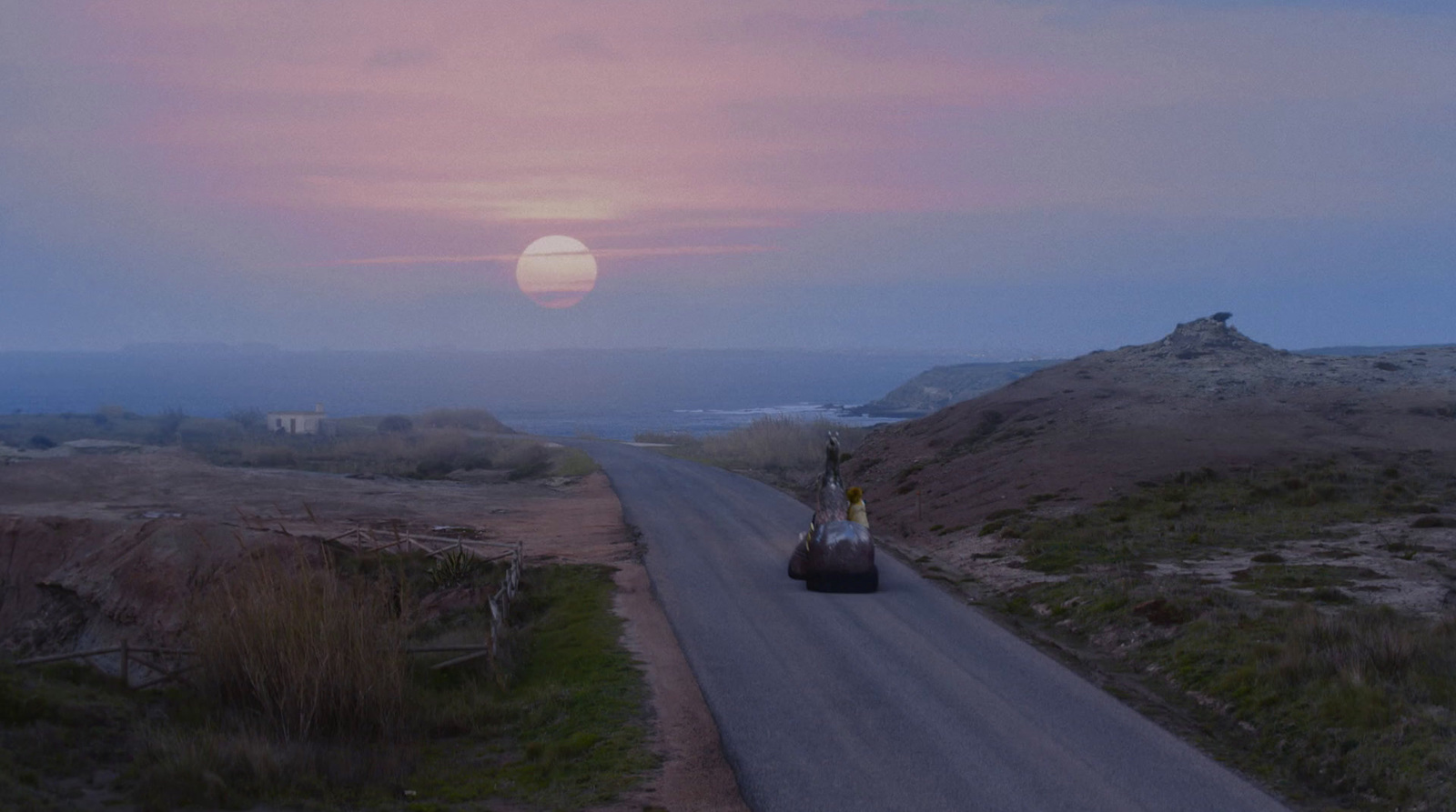 a car driving down a road with a sunset in the background