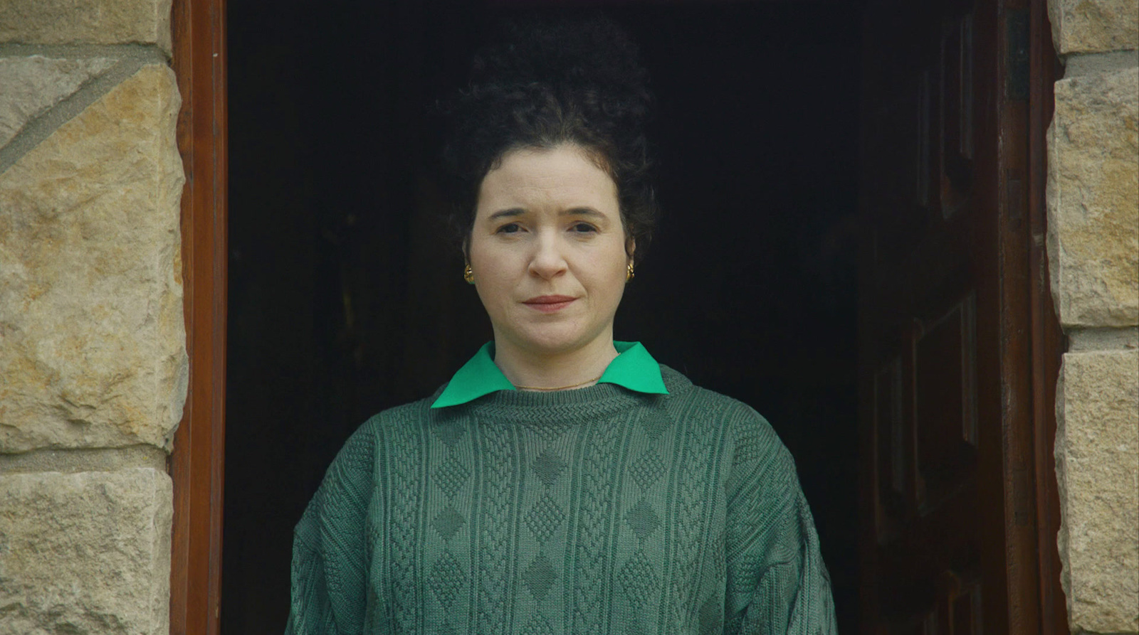 a woman in a green sweater looking out of a window