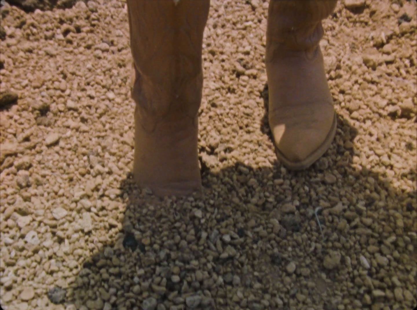 a person standing in the dirt with a pair of boots