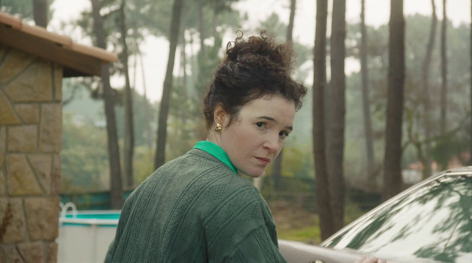 a woman standing next to a green car