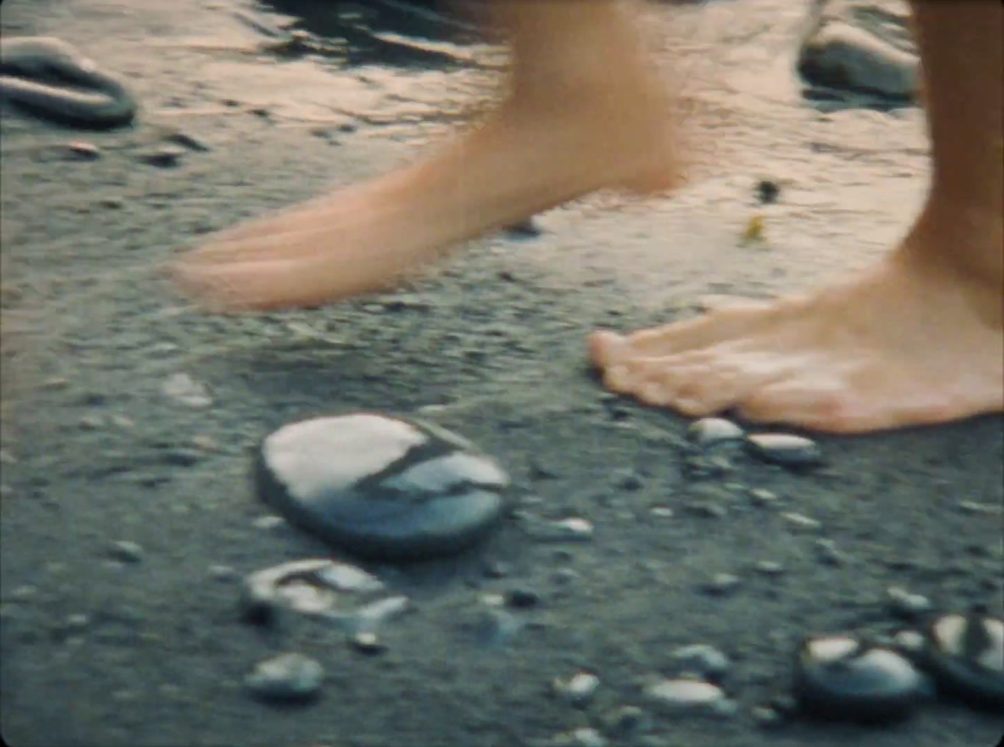 a person standing on a beach next to rocks and water