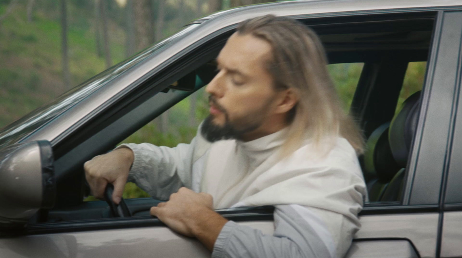 a man with long hair sitting in a car