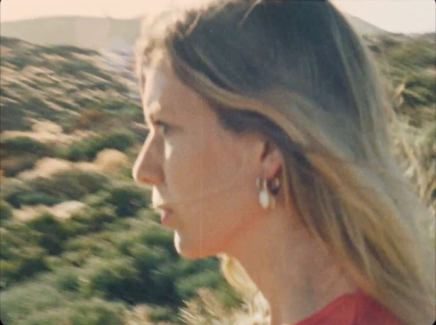 a woman in a red shirt is looking off into the distance