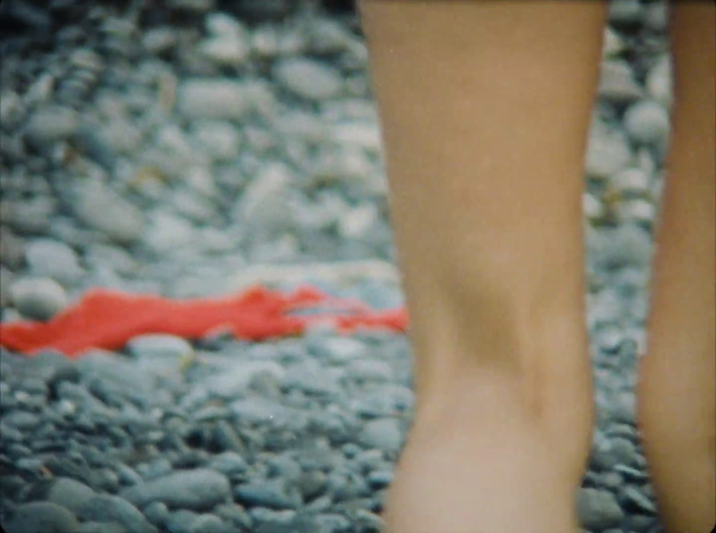 a close up of a person's legs on a pebble beach