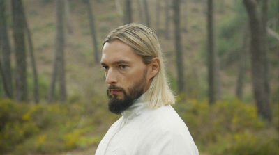 a man with long hair and a beard in the woods