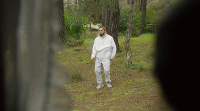 a man in a white suit standing in the woods