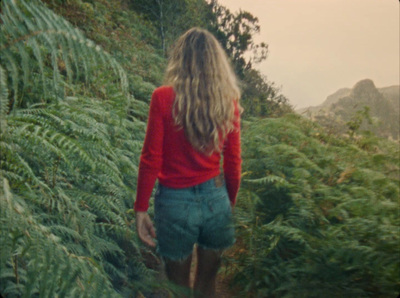 a woman walking through a lush green forest