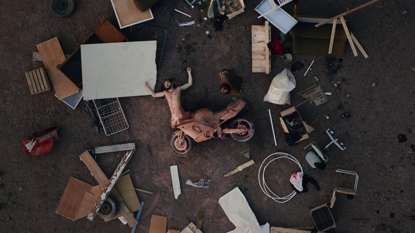 a man laying on the ground surrounded by junk