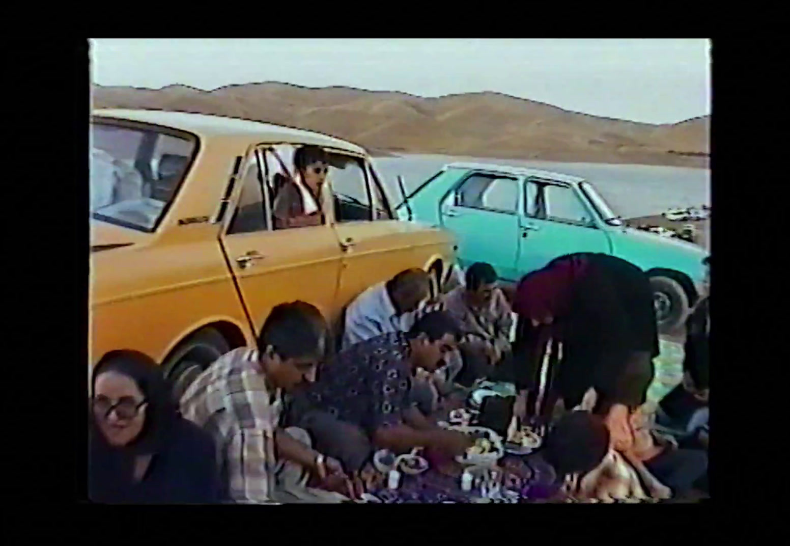 a group of people sitting around a yellow car