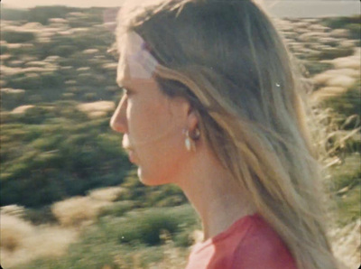 a woman with long blonde hair walking through a field