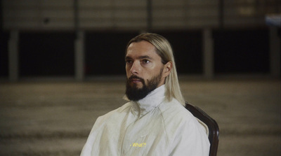 a man with long hair and a beard wearing a white shirt