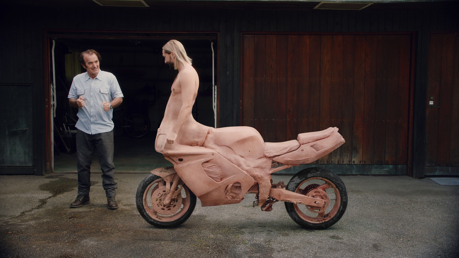 a man standing next to a pink sculpture of a motorcycle