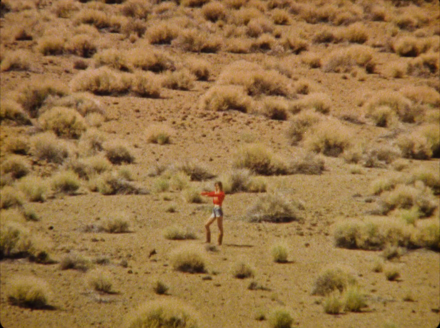 a person in the middle of a desert with a frisbee