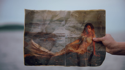 a person holding up a picture of a mermaid