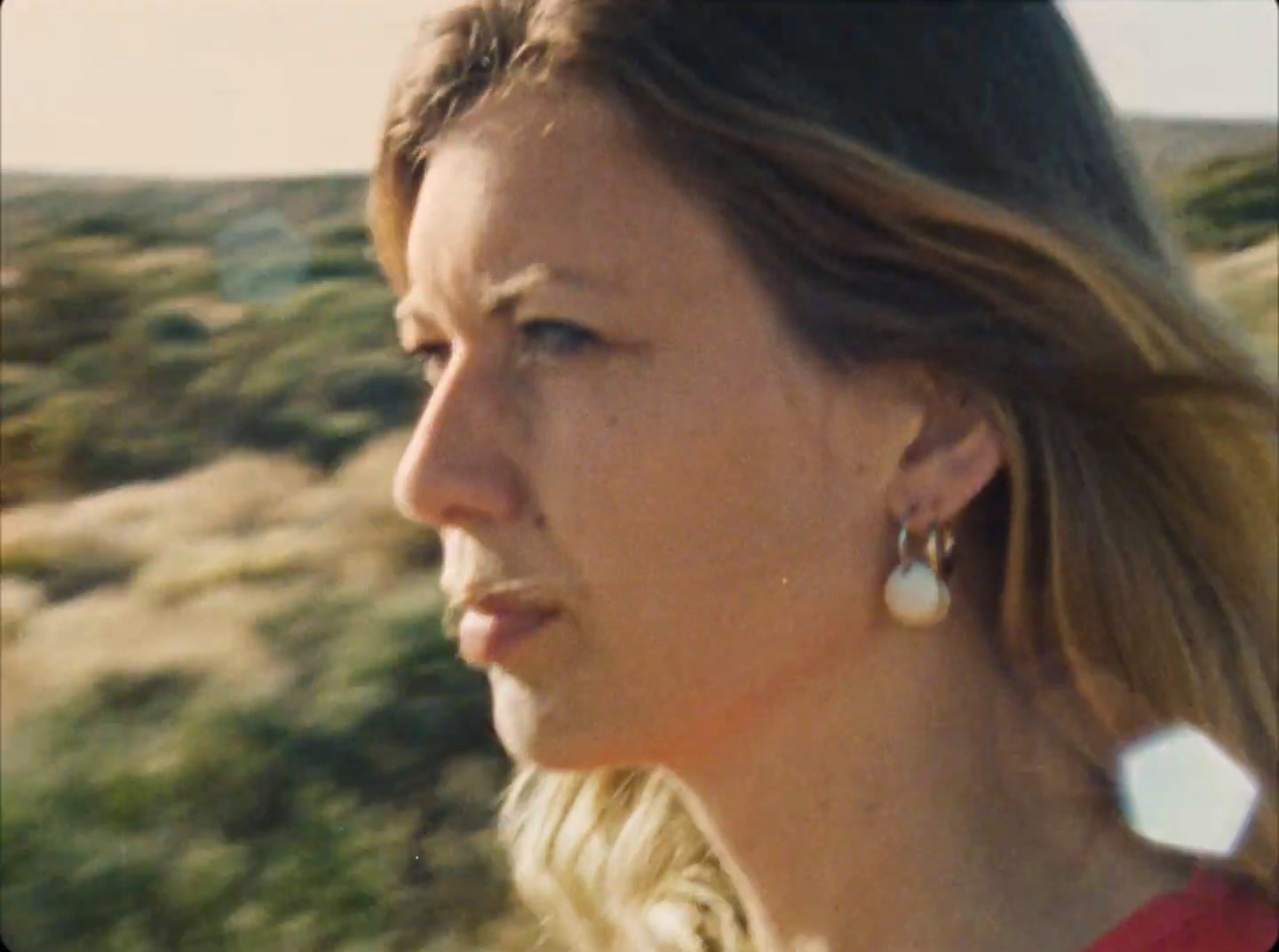 a woman in a red shirt is looking off into the distance