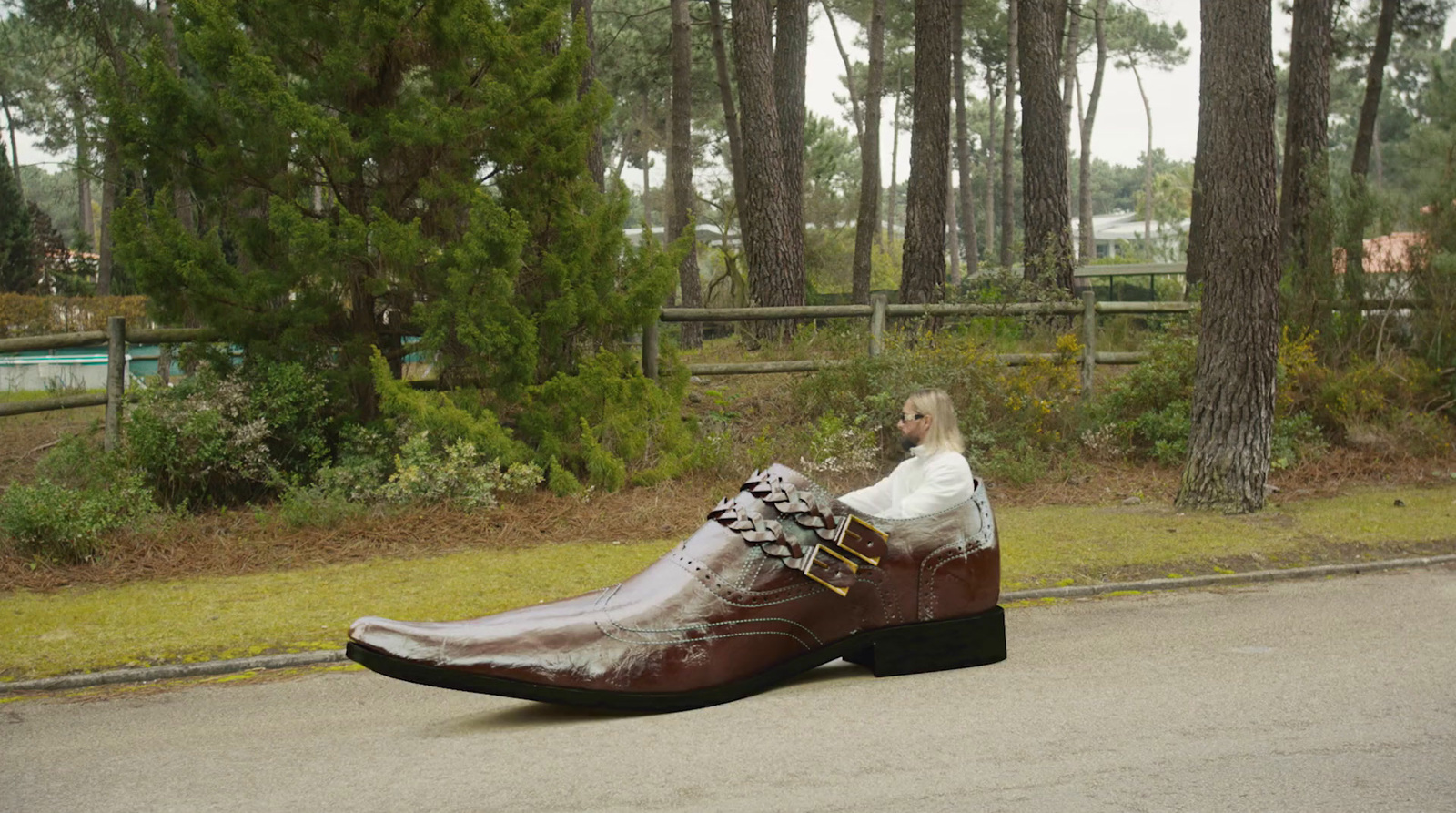 a woman sitting on top of a shoe on the side of a road