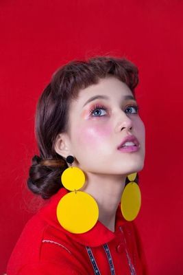 a woman in a red shirt and yellow earrings