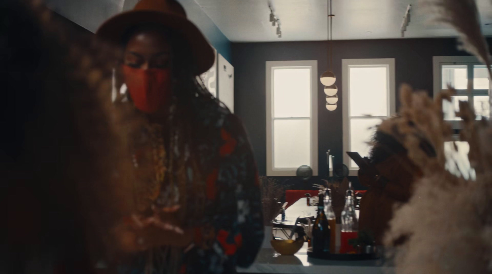 a woman wearing a red mask standing in a kitchen