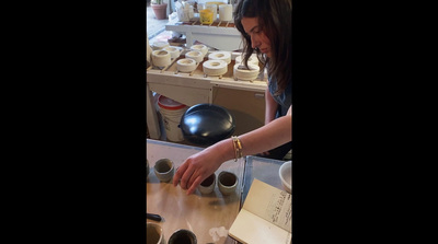 a woman is making a doughnut at a doughnut shop