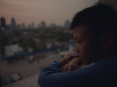 a young boy leaning on a ledge with a city in the background