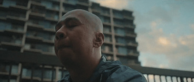 a man with a bald head standing in front of a tall building