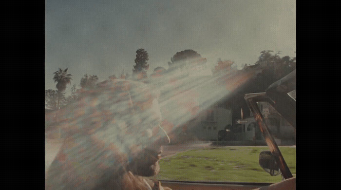 a man driving a car with the sun shining through the windshield