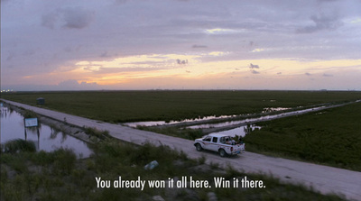 a white truck driving down a road next to a lush green field