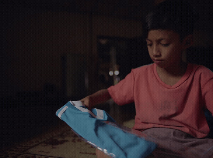 a little girl sitting on the floor opening a bag