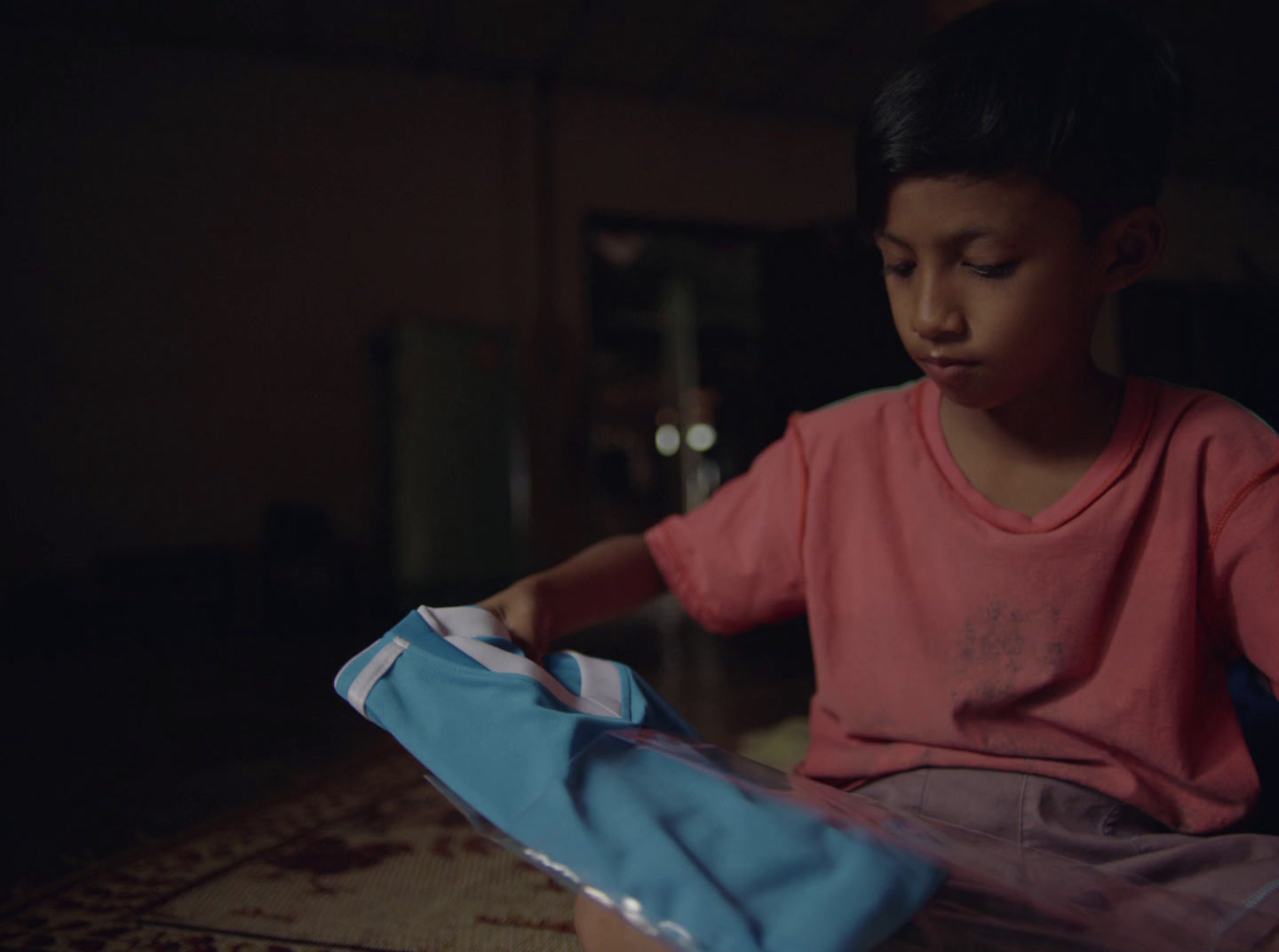 a young boy sitting on the floor opening a bag