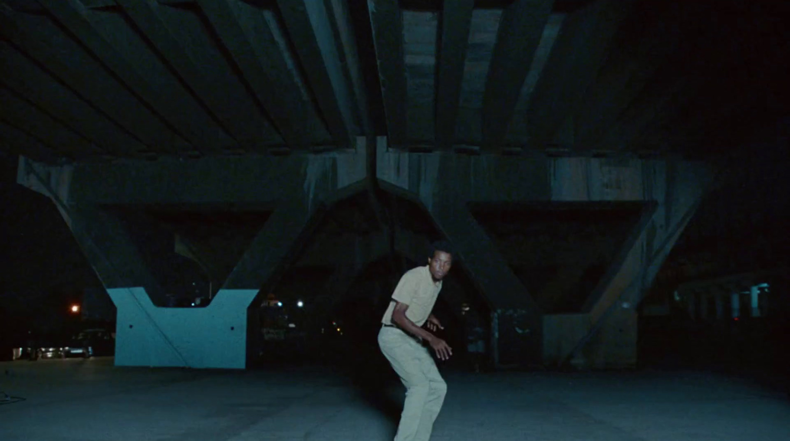 a man in a white shirt is skateboarding under a bridge