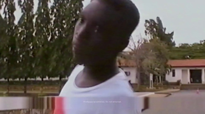 a man in a white t - shirt standing in front of a tree