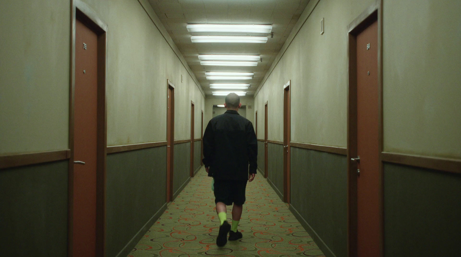 a man walking down a long hallway in an office building