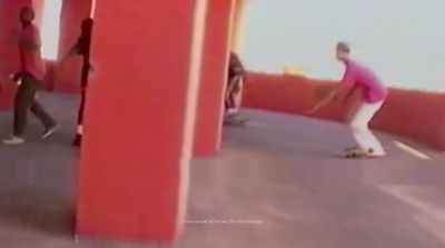 a man riding a skateboard down a street next to tall red pillars