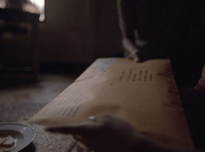 a person holding a brown paper bag with writing on it