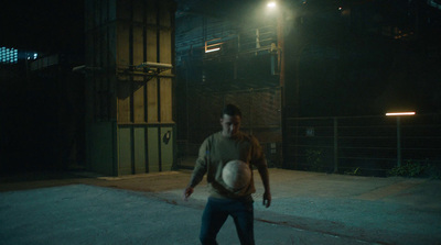 a man holding a soccer ball on a street at night