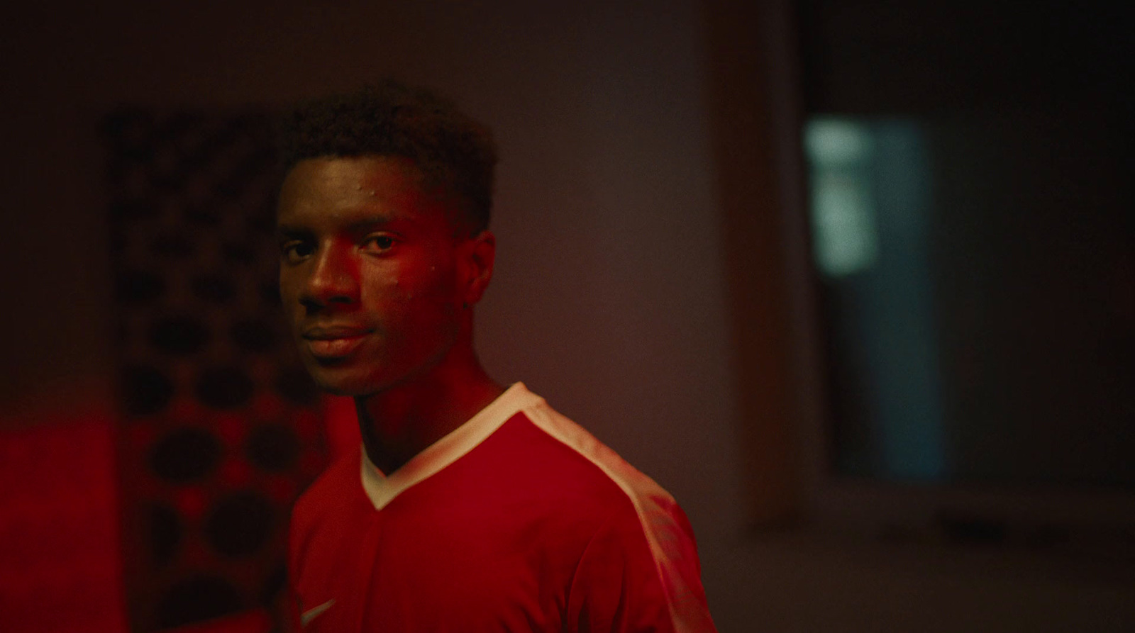 a man in a red shirt is standing in a dark room