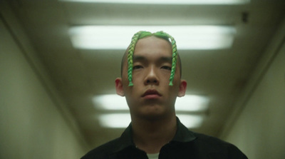 a man with green hair standing in a hallway