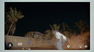 a man riding a skateboard down a street next to palm trees