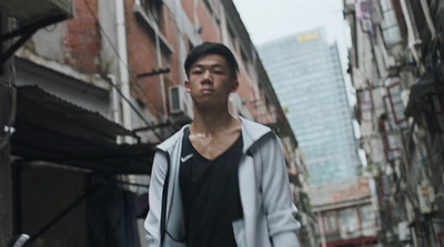 a man walking down a street next to tall buildings