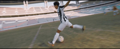 a man kicking a soccer ball on top of a field