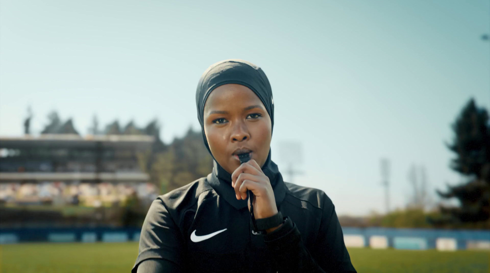 a woman in a black jacket is holding a finger to her mouth