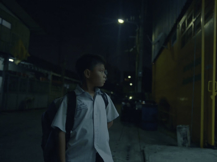 a young boy standing on a sidewalk at night