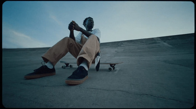 a man sitting on the ground with his feet on a skateboard