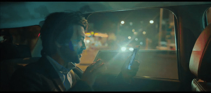 a man sitting in a car using a cell phone