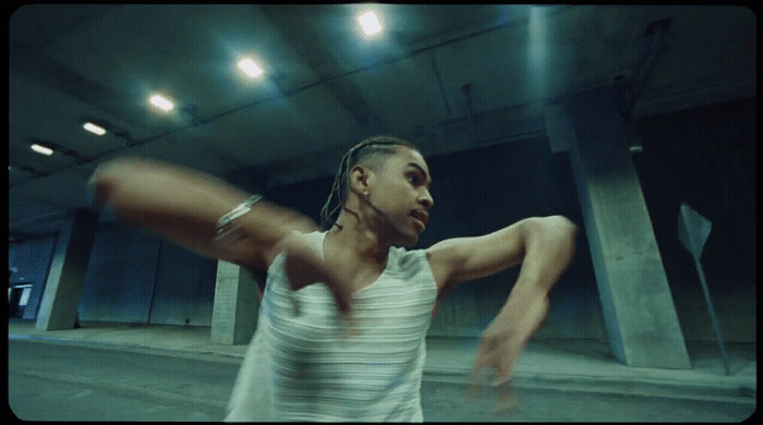 a man with dreadlocks standing in a parking garage