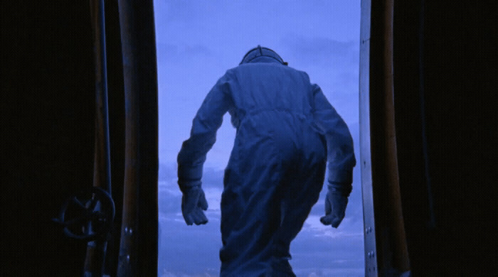 a man in a white suit walking out of a doorway